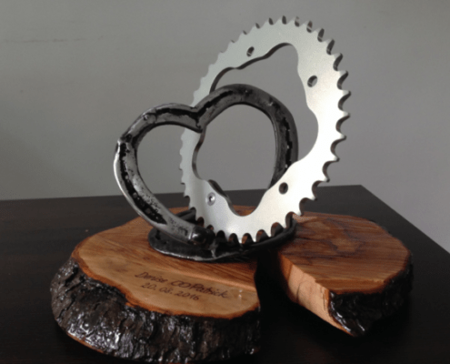 wedding present - Connection of a heart made of horseshoes and a sprocket fixed on an engraved wooden plate.