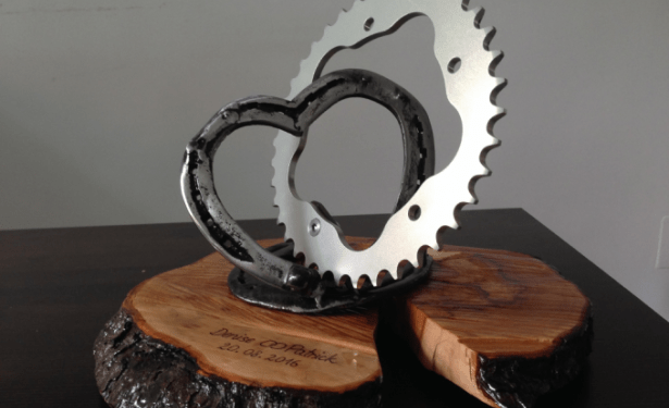 wedding present - Connection of a heart made of horseshoes and a sprocket fixed on an engraved wooden plate.